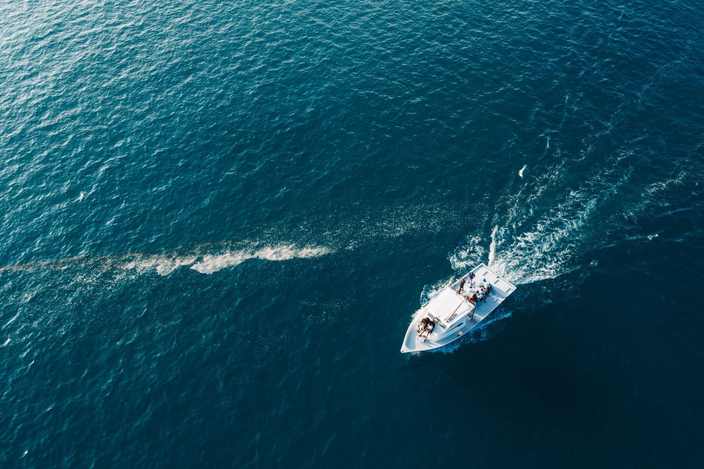 Aerial view of a boat carving a wake across open blue water